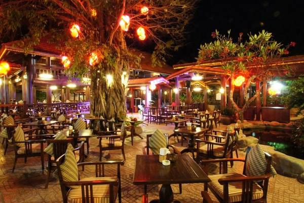 Hotellounge des Novela Muine Resort & Spa bei Nacht mit beleuchteten Bäumen und Tischen.