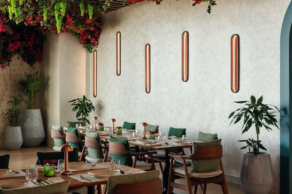Restaurantbereich im St. Regis Al Mouj Muscat Resort mit Tisch, Stühlen, Pflanzen und Wandleuchten.