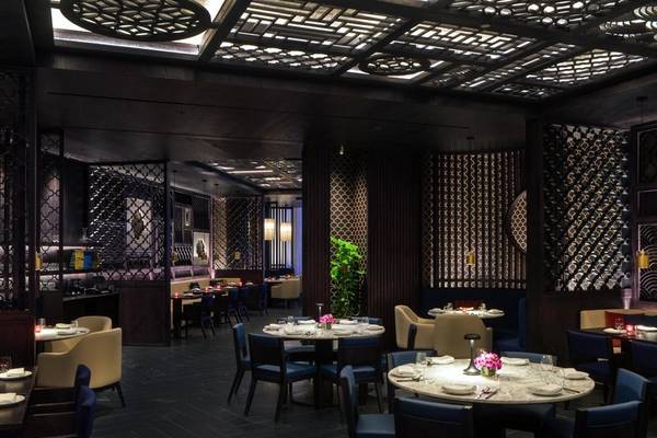 Innenansicht des Restaurants im St. Regis Al Mouj Muscat Resort mit dunklen Möbeln und goldenen Akzenten.