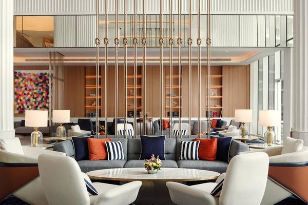 Lobby des St. Regis Al Mouj Muscat Resorts mit Sofas, Lampen und Kunstwerk.