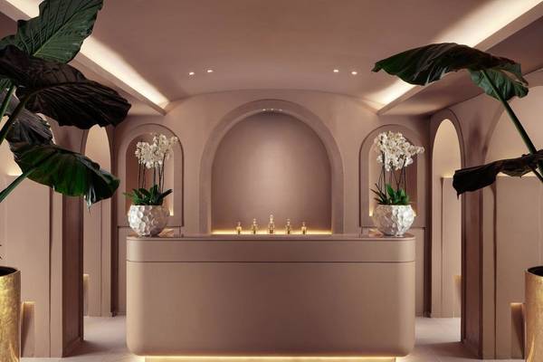 Empfangsbereich des St. Regis Al Mouj Muscat Resorts mit einer Theke, Blumenvasen und Beleuchtung.