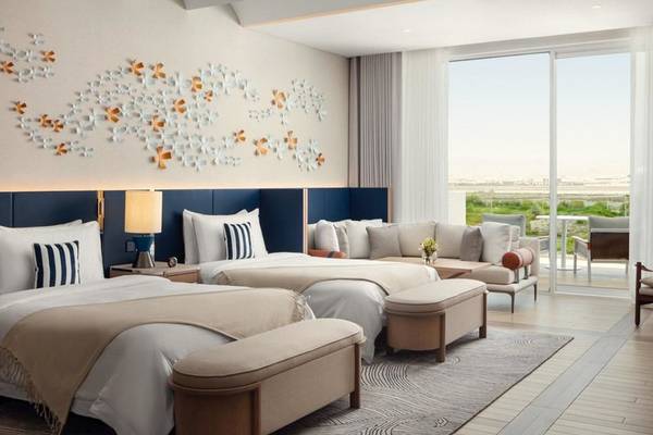 Doppelzimmer im St. Regis Al Mouj Muscat Resort mit zwei Betten und Blick auf den Garten.