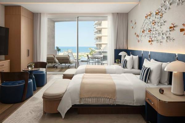Schlafzimmer im St. Regis Al Mouj Muscat Resort mit Meerblick und zwei Betten.