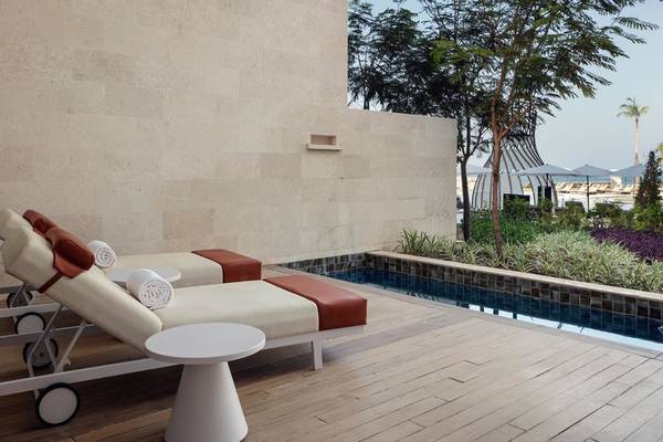 Lounge-Bereich des St. Regis Al Mouj Muscat Resorts mit Swimmingpool und Liegen