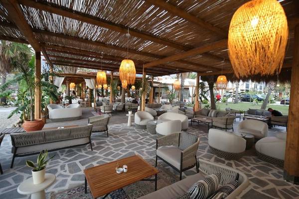 Terrasse des Oricon Coast Luxury Resorts mit Rattan-Überdachungen, Sesseln und Tischen, umgeben von Pflanzen.
