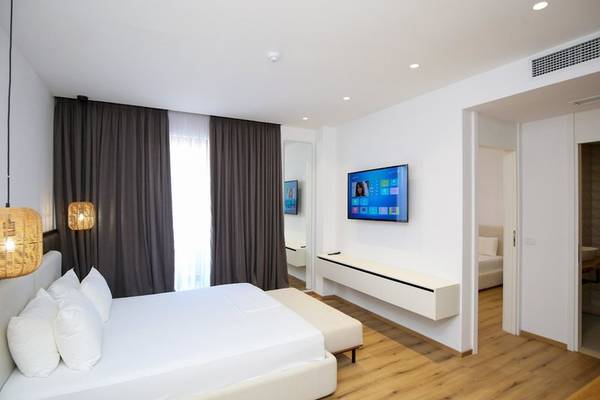 Innenansicht eines Schlafzimmers im Oricon Coast Luxury Resort mit einem großen Bett, Kissen und Fernseher.