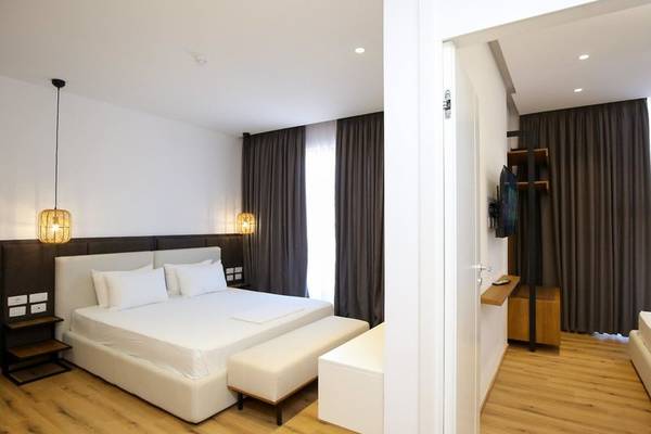 Schlafzimmer im Oricon Coast Luxury Resort mit Doppelbett, weißen Möbeln und modernen Beleuchtungskörpern.