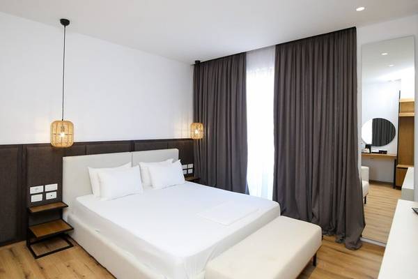 Innenansicht eines Hotelzimmers im Oricon Coast Luxury Resort mit weißem Bett, grauen Vorhängen und hölzerne Boden.
