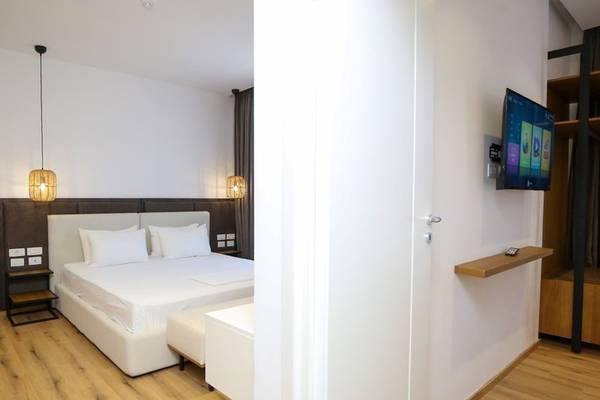Innenansicht eines eleganten Hotelzimmers mit Doppelbett, Flachbildfernseher an der Wand und Holzboden.