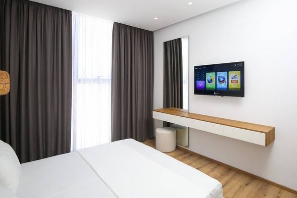 Innenansicht eines Zimmers im Oricon Coast Luxury Resort mit einem Bett, Fernseher, und Nachttisch.