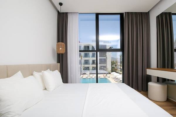 Schlafzimmer mit Poolblick im Oricon Coast Luxury Resort mit weißem Bett, Kissen und Fenstern mit Blick auf den Pool.