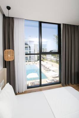 Ein Zimmer im Oricon Coast Luxury Resort mit Aussicht auf den Pool und Sonnenliegen.