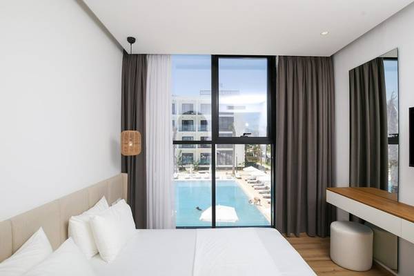 Hotelzimmer mit Poolblick im Oricon Coast Luxury Resort mit großem Bett und Sonnenschirmen.