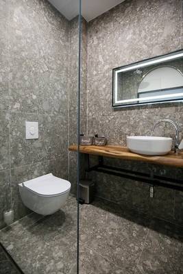 Badezimmer des Oricon Coast Luxury Resort mit grauen Wänden und Bodenfliesen, einer Dusche, einem Waschbecken und einem Toilettensitz.