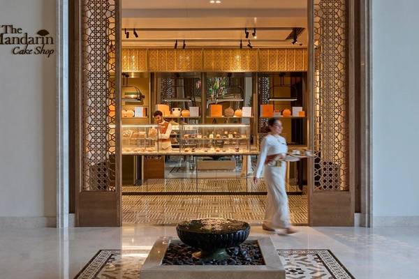 Eingang zur Mandarin Oriental Muscat Cake Shop mit zwei Angestellten und einer Kundin.