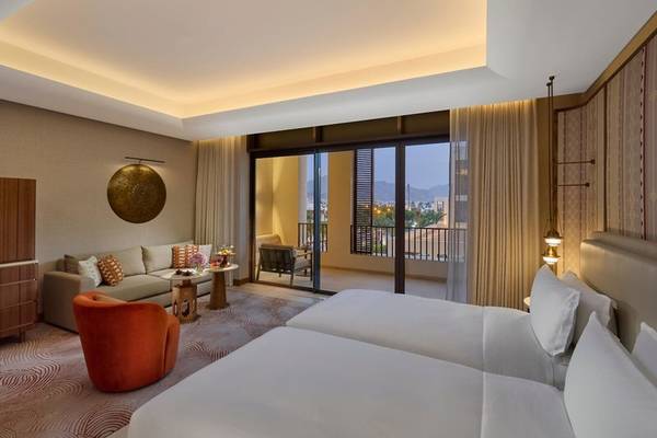 Schlafzimmer im Mandarin Oriental, Muscat mit zwei Betten und Blick auf die Stadt.
