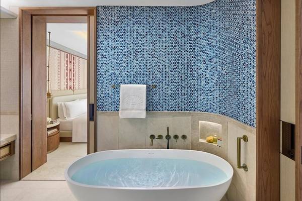 Badezimmer im Mandarin Oriental, Muscat, mit großer Badewanne und blauen geometrischen Wänden.