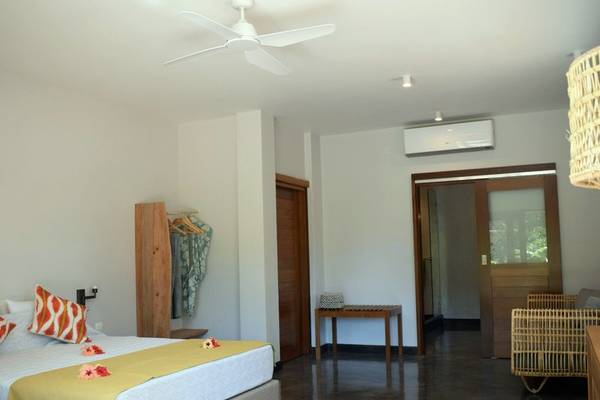 Hotelzimmer mit Bett, Tisch, Deckenventilator und Türen im Les Lauriers Eco Hotel & Restaurant.