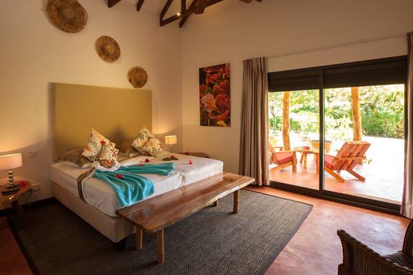 Innenansicht eines Zimmers im Les Lauriers Eco Hotel mit Bett, Dekor und Terrassenzugang
