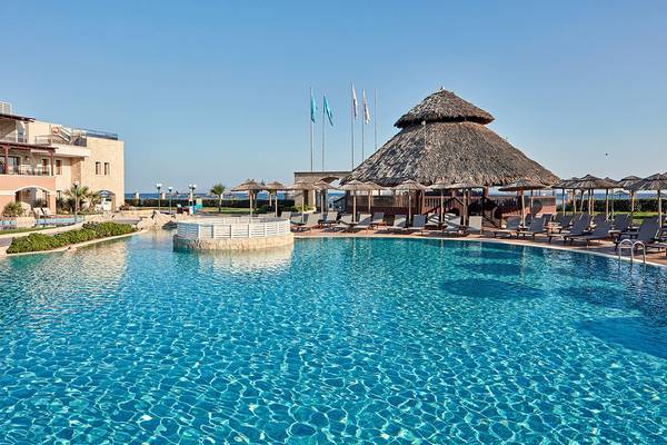 Außenpoolbereich des Atlantica Caldera Palace Hotels mit Liegestühlen und Sonnenschirmen.