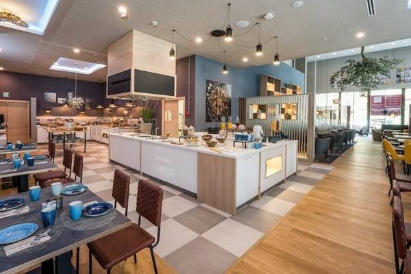 Innenansicht des Restaurants im Leonardo Royal Hotel Barcelona Fira mit Buffet, Tischen und Stühlen.