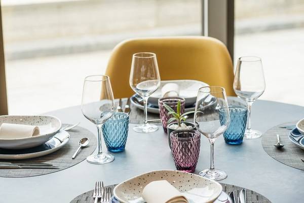 Gedeckter Tisch im Leonardo Royal Hotel Barcelona Fira mit Gläsern, Tellern und Besteck.