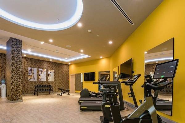 Fitnessstudio im Leonardo Royal Hotel Barcelona Fira mit gelben Wänden und Fitnessgeräten.