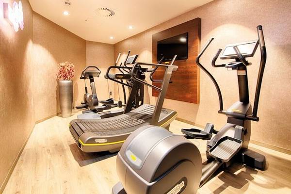 Fitnessraum im Leonardo Royal Hotel Barcelona Fira mit Laufbändern, Rudergeräten und Fernseher.