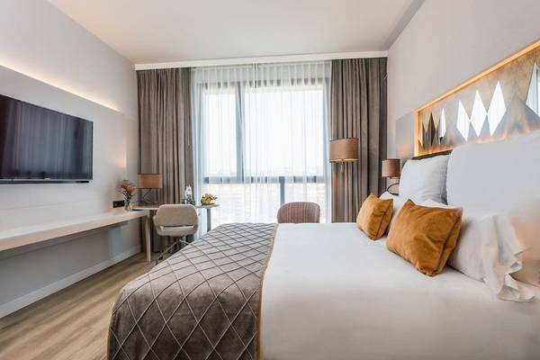 Schlafzimmer im Leonardo Royal Hotel Barcelona Fira mit Bett, Schreibtisch und Fernseher
