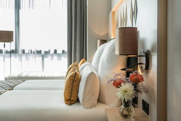 Schlafzimmer im Leonardo Royal Hotel Barcelona Fira mit Bett, Kissen und Blumenvase