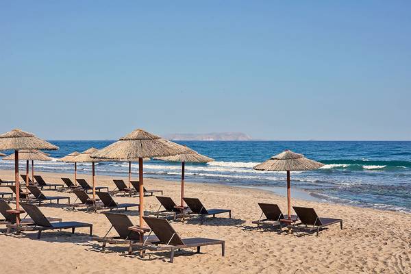 Strand des Atlantica Caldera Palace Hotels mit Sonnenliegen und Sonnenschirmen