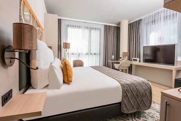 Schlafzimmer im Leonardo Royal Hotel Barcelona Fira mit Bett, Schreibtisch und Fernseher.