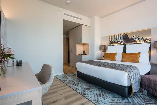 Innenansicht eines modernen Hotelzimmers im Leonardo Royal Hotel Barcelona Fira mit einem Bett, Schreibtisch und Dekor.
