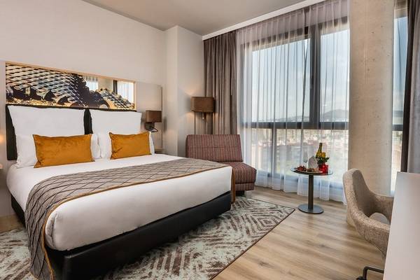 Schlafzimmer im Leonardo Royal Hotel Barcelona Fira mit Doppelbett, Fenstern und moderner Einrichtung.