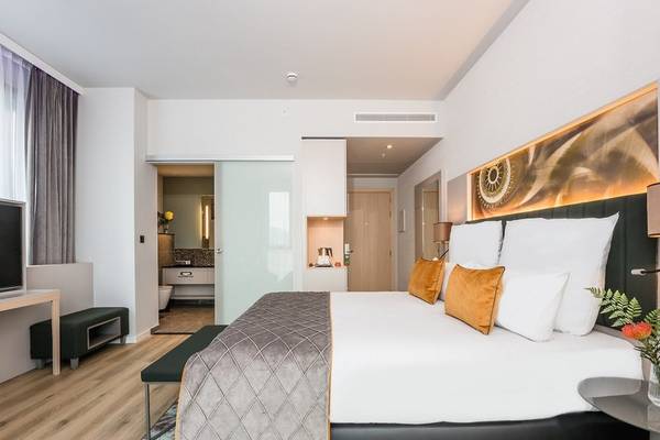 Ein modernes Hotelzimmer im Leonardo Royal Hotel Barcelona Fira mit großem Bett und stilvoller Einrichtung.