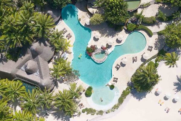 Luftaufnahme des Pools im Le Bora Bora by Pearl Resorts mit mehreren Sonnenliegen und Sonnenschirmen.