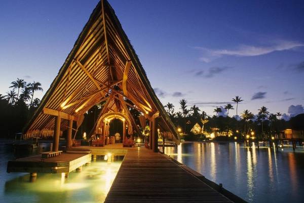 Nachtansicht des Le Bora Bora by Pearl Resorts, einem Hotelgebäude auf dem Wasser.