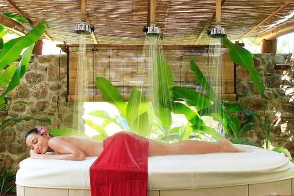 Frau in einem roten Tuch unter einer tropischen Dusche im Le Bora Bora by Pearl Resorts
