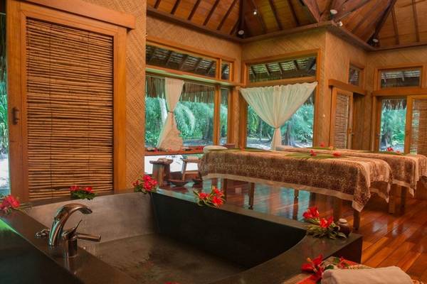 Massageraum im Le Bora Bora by Pearl Resorts mit einem großen Badewanne und zwei Massagetischen.
