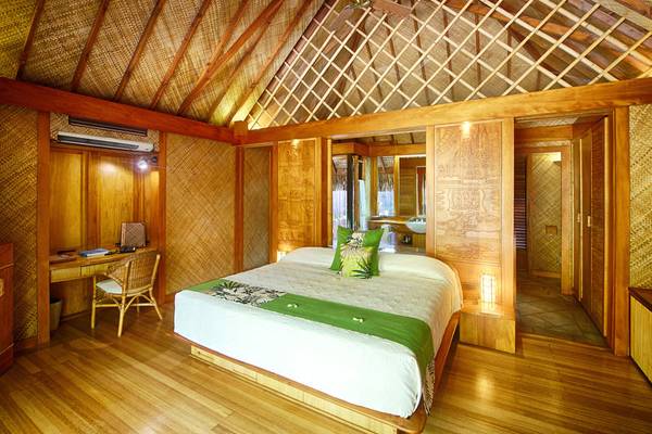 Innenansicht eines Zimmers im Le Bora Bora by Pearl Resorts mit Holzboden, Bett, Schreibtisch und Deckenventilator