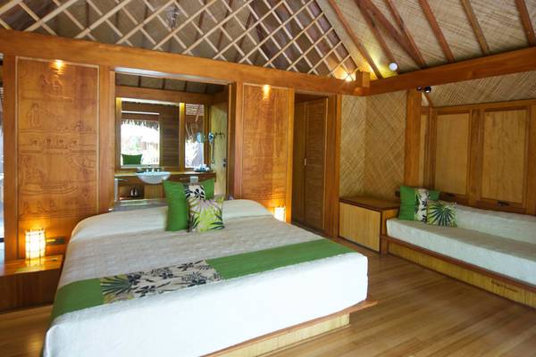 Schlafzimmer im Le Bora Bora by Pearl Resorts mit Bett, Sofa, Holzwand und Badezimmerspiegel