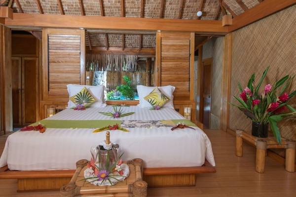 Schlafzimmer im Le Bora Bora by Pearl Resorts mit Bett, Blumen, und Dekor