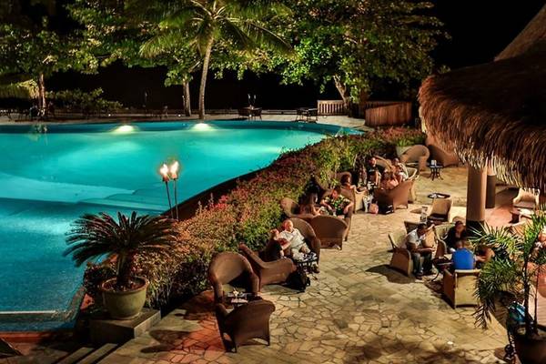 Poolbereich des Le Tahiti by Pearl Resorts bei Nacht mit Gästen und Palmen