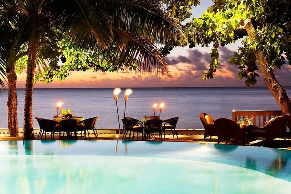 Pool des Le Tahiti by Pearl Resorts bei Sonnenuntergang mit Meerblick und abendlicher Beleuchtung.