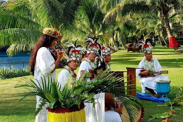 Musikgruppe im Le Tahiti by Pearl Resorts, die vor einer Kulisse von Palmen und einem See spielt.
