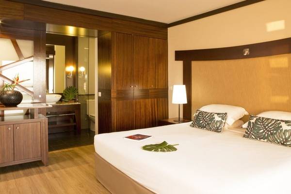 Schlafzimmer des Le Tahiti by Pearl Resorts Hotels mit Bett, Kissen und Lampe.