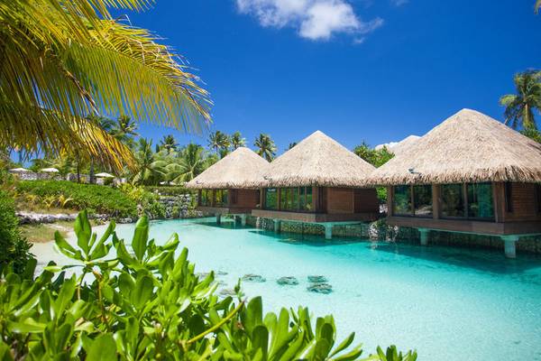 Drei Wasserbungalows des InterContinental Bora Bora Resorts mit blauem Wasser und grüner Vegetation.
