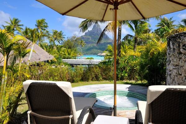 Außenbereich des InterContinental Bora Bora Resorts mit zwei Loungestühlen und einem Sonnenschirm.