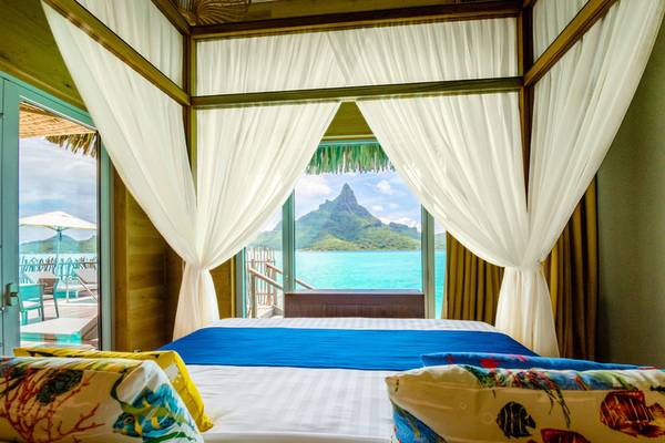 Ein Bett in einem Hotelzimmer mit Aussicht auf den Berg und das Meer.