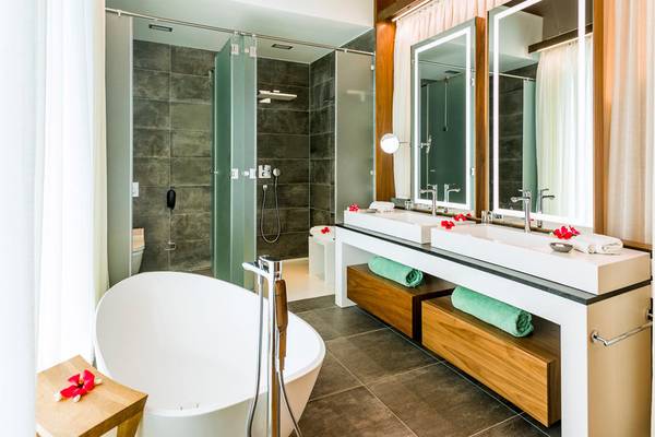 Ein elegantes Badezimmer im InterContinental Bora Bora Resort mit Badewanne, Dusche und zwei Waschbecken.